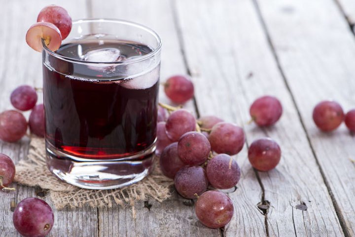 Glas hausgemachter roter Traubensaft mit frischen Trauben