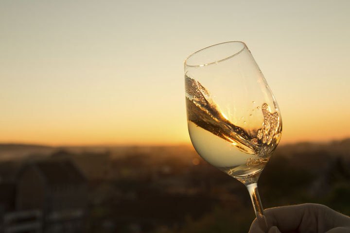 Glas Weißwein im Abendlicht über Wien